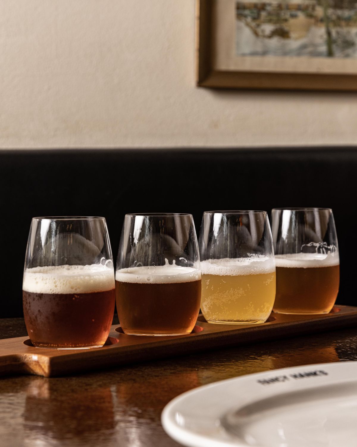 A wooden paddle of four tasting beers on a table at Fancy Hank's