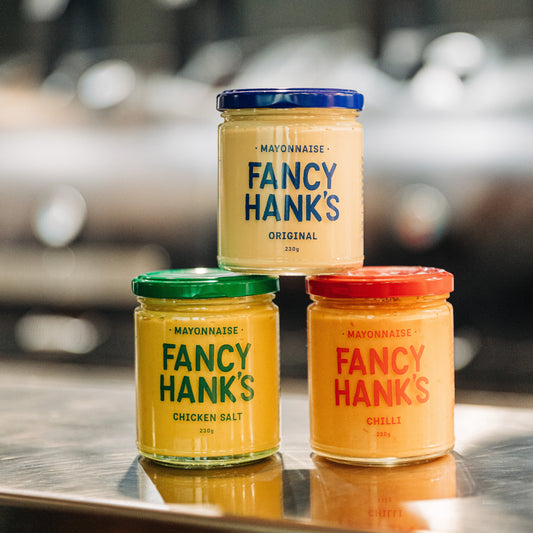 Three jars of Fancy Hank's mayonnaise sitting on a bench in the Fancy Hank's Restaurant kitchen